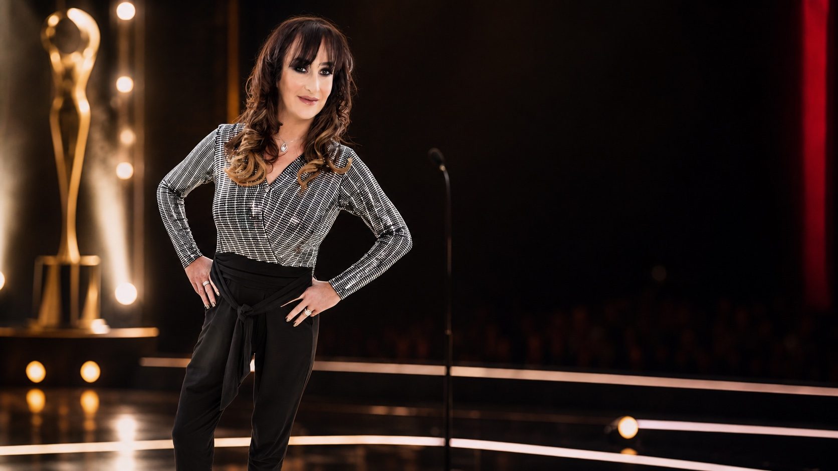 Gina McKie hosting on an awards stage under theatre lighting